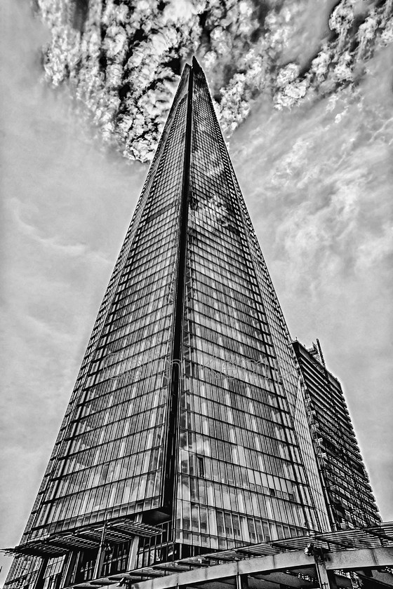 Shard Black and White Photograph DSC2714-E2 
 The Shard, modern icon of the London skyline stands proud against a dramatic sky. Taken from close to the base with a wide angle lens. Just a little creative licence emp;yed to crop out a crane and errant building in the top corners, allowing this fabulous building to star unopposed. 
 Keywords: Black and White, Shard, Urban, Architect Piano, London skyline, Modern icons,