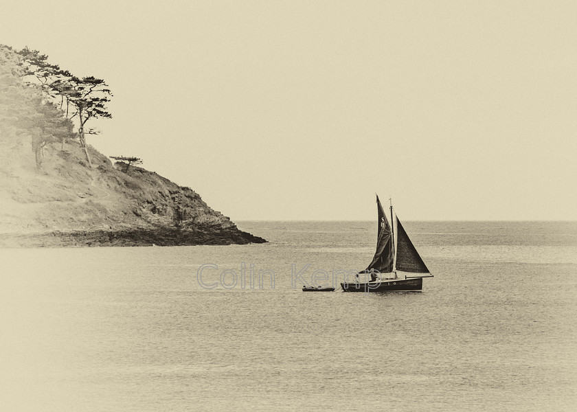 0001CK 4662-Edit-Edit 
 Monochrome image of traditional fishing boat leaving a Cornwall harbour under sail slipping past a headland. 0001CK_4662EE 
 Keywords: Cornwall black and white fishing boat headland monochrome